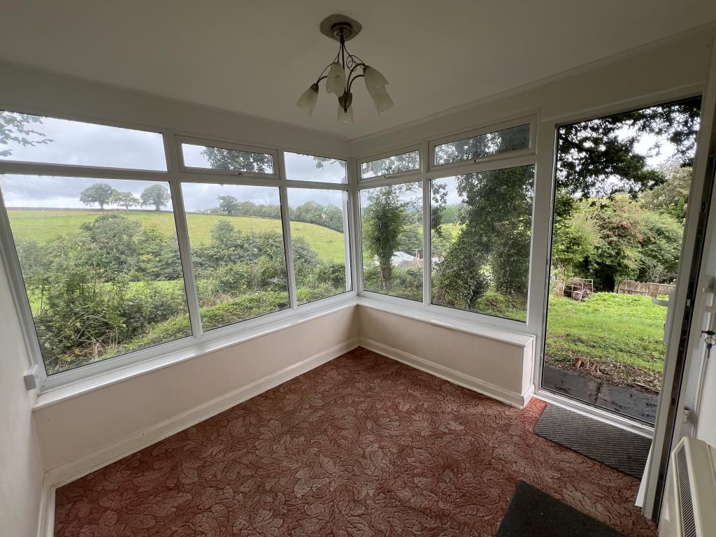Lot: 115 - COTTAGE FOR REFURBISHMENT WITH LARGE GARDEN AND PARKING, PLUS SEPARATE PADDOCK - View of the conservatory showing the rural outlook